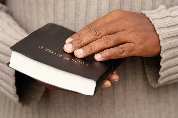 A black man holding a black Bible to depict the dangers of overreliance on Bible reading plans