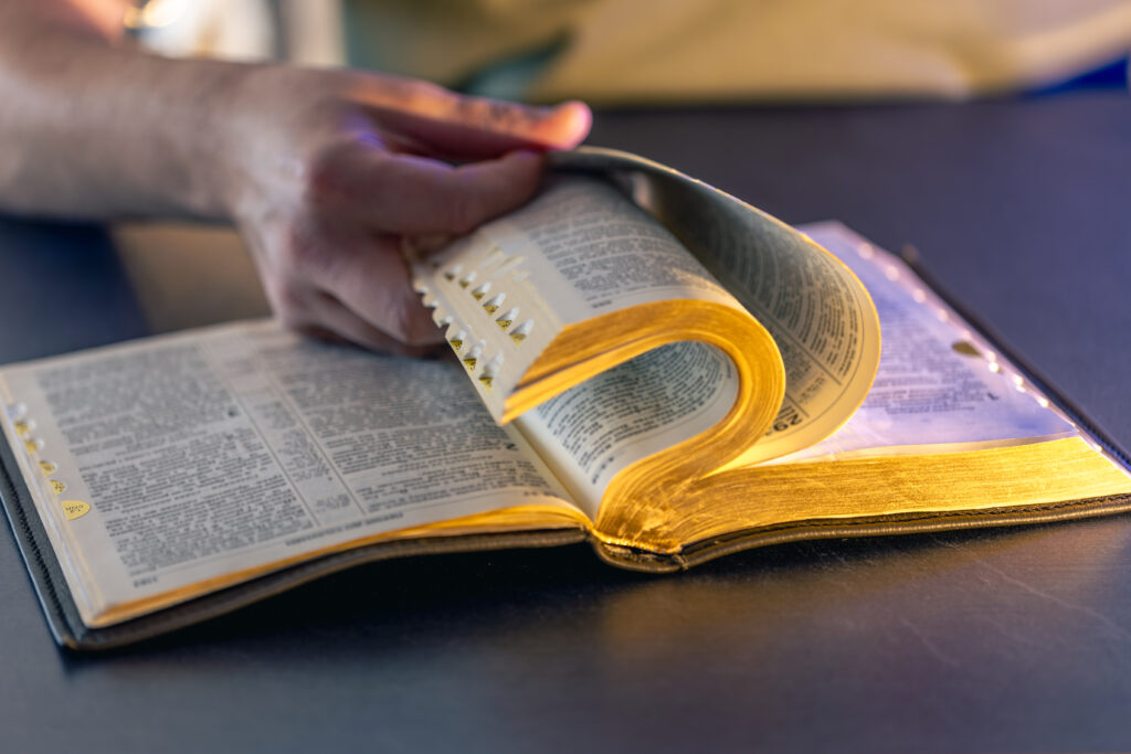 A close up of a man reading the Bible: a male hands on the Holy Bible