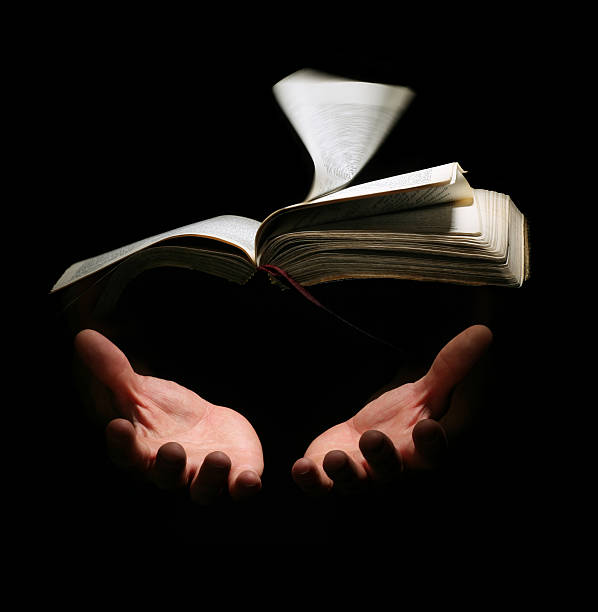 A Bible floating on the air with two hands waiting to receive it