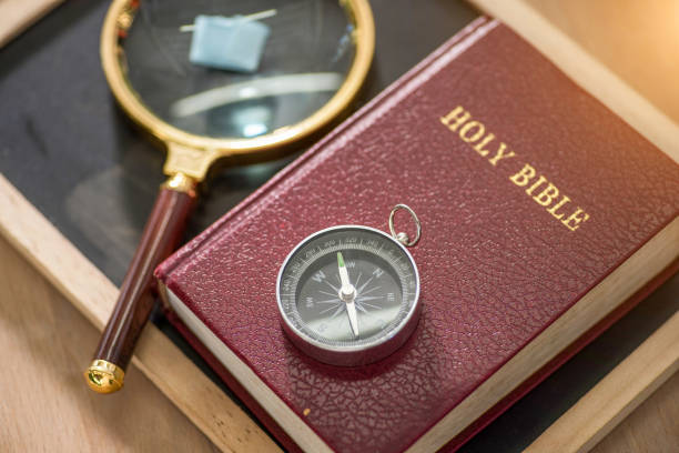 Close up of compass on holy bible over wood desk background