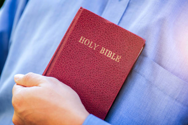 A man dressed in a blue shirt holding a Bible to illustrate the point of obedience