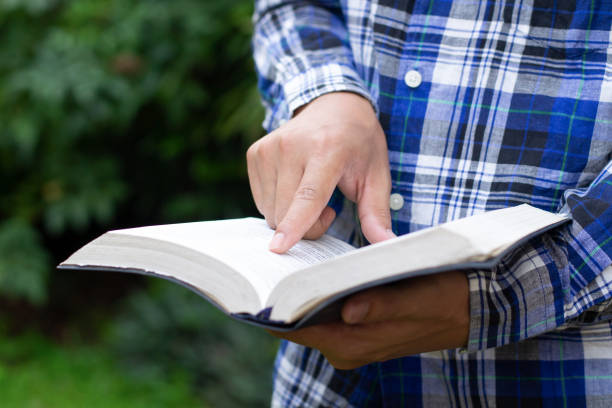 A man reading the bible with fingers pointing at the text as signified by Bible study