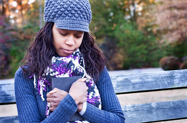 Woman with eyes closed clutching bible for Bible retention hacks
