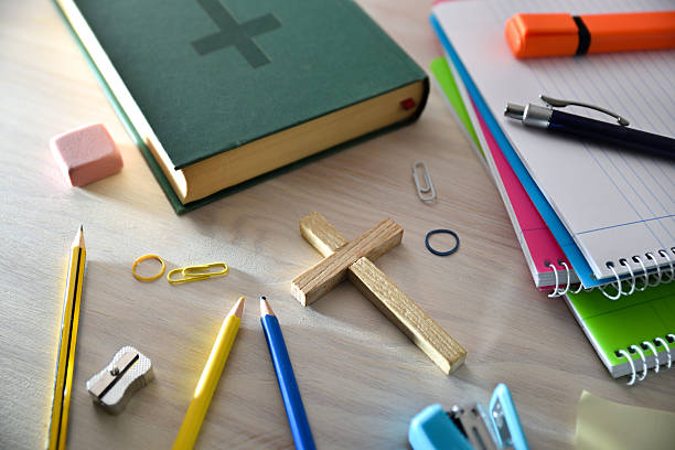 A green Bible with several tools and educational materials on a wooden table