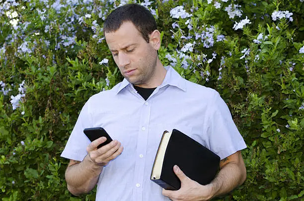 Someone holding the Bible while looking at the phone to depict removing distractions