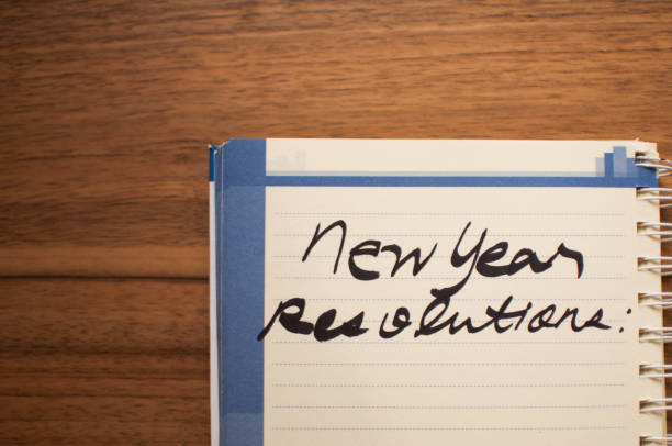 New Year Resolution written in a notepad over the wooden table