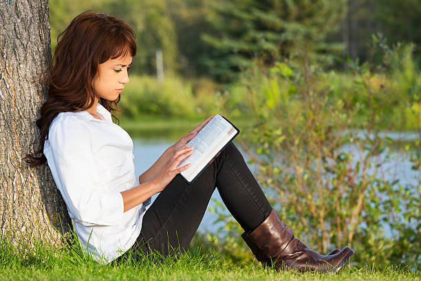 A young girl reading the Bible outdoors to illustrate experiencing God for the reasons consistent Bible reading should be part of your annual planning
