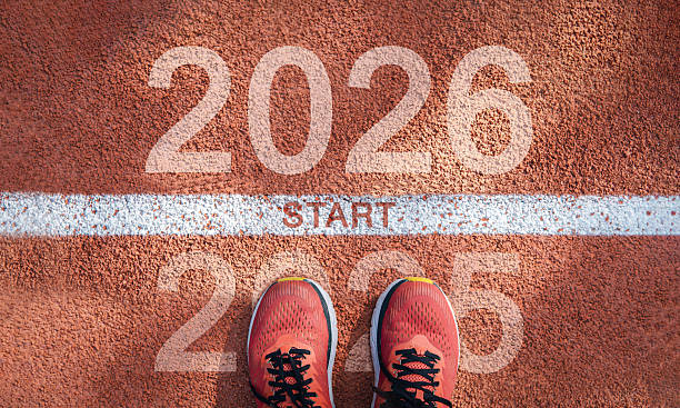Text 2026 written on asphalt road and male runner preparing for the new year. Concept of challenge or career path and change. A concept to illustrate locking it into plans