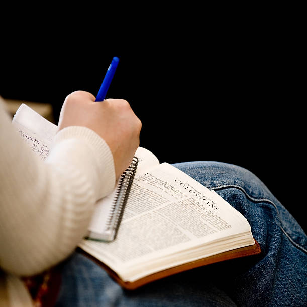 A young female takes notes during a sermon with open bible in her lap