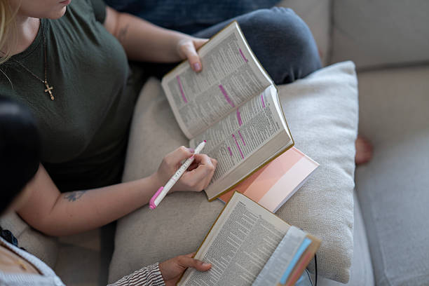A group of women studying religious text together, highlighting key passages and taking notes to highlight comparing notes