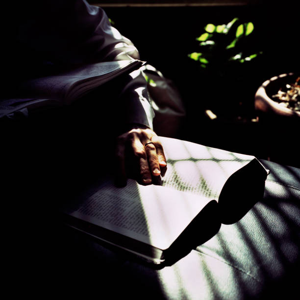 Someone reading the Bible with hands visible against a dark background