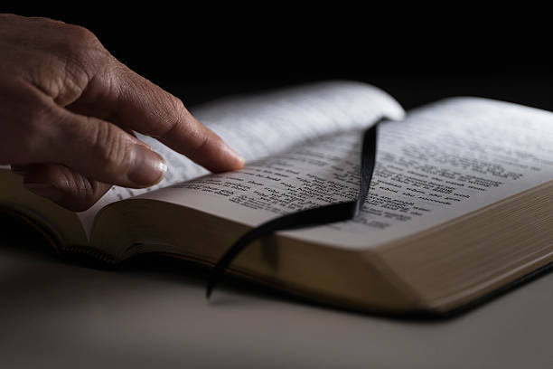 A Bible laid open with a finger pointed on the text to depict examining context