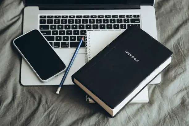 A Bible, notebook, phone, and pencil on a laptop to illustrate self-audit